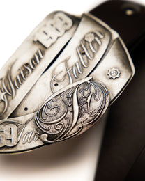 Close-up of a detailed metal belt buckle with engraved text and designs.