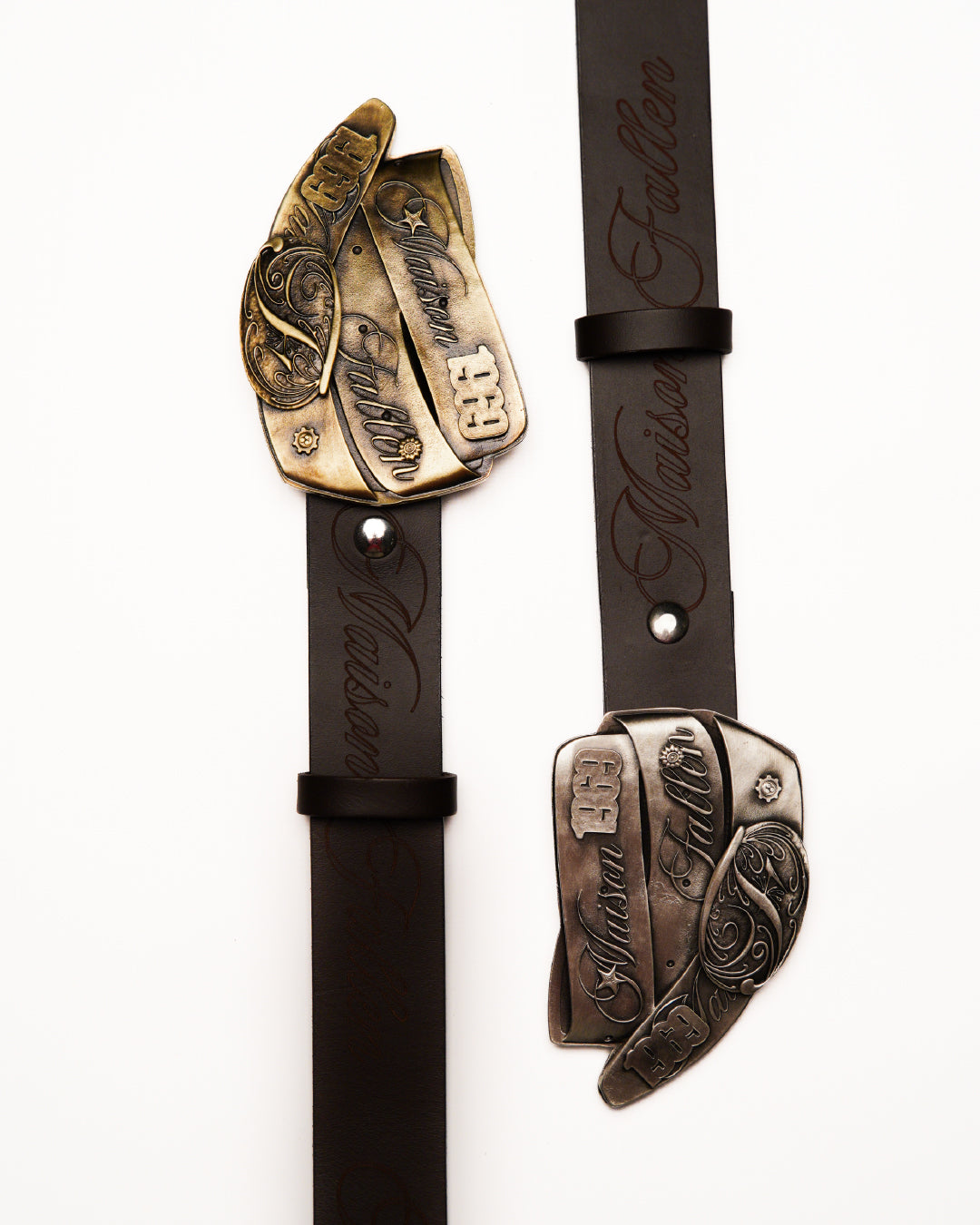 Two leather straps with metal ends featuring intricate designs on a white background.